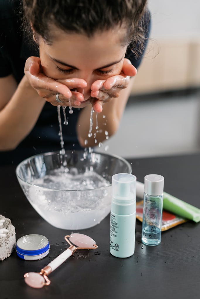 A woman practicing her perimenopausal sensitive and redness skincare routine with a face wash and products on a counter.