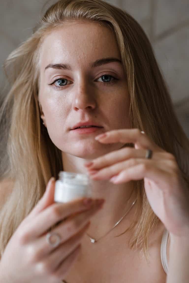 Close-up of a woman holding a skincare cream jar, emphasizing beauty and self-care.