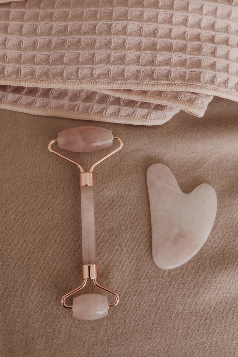 Flat lay of a rose quartz skincare tool set and towels for a wellness routine.