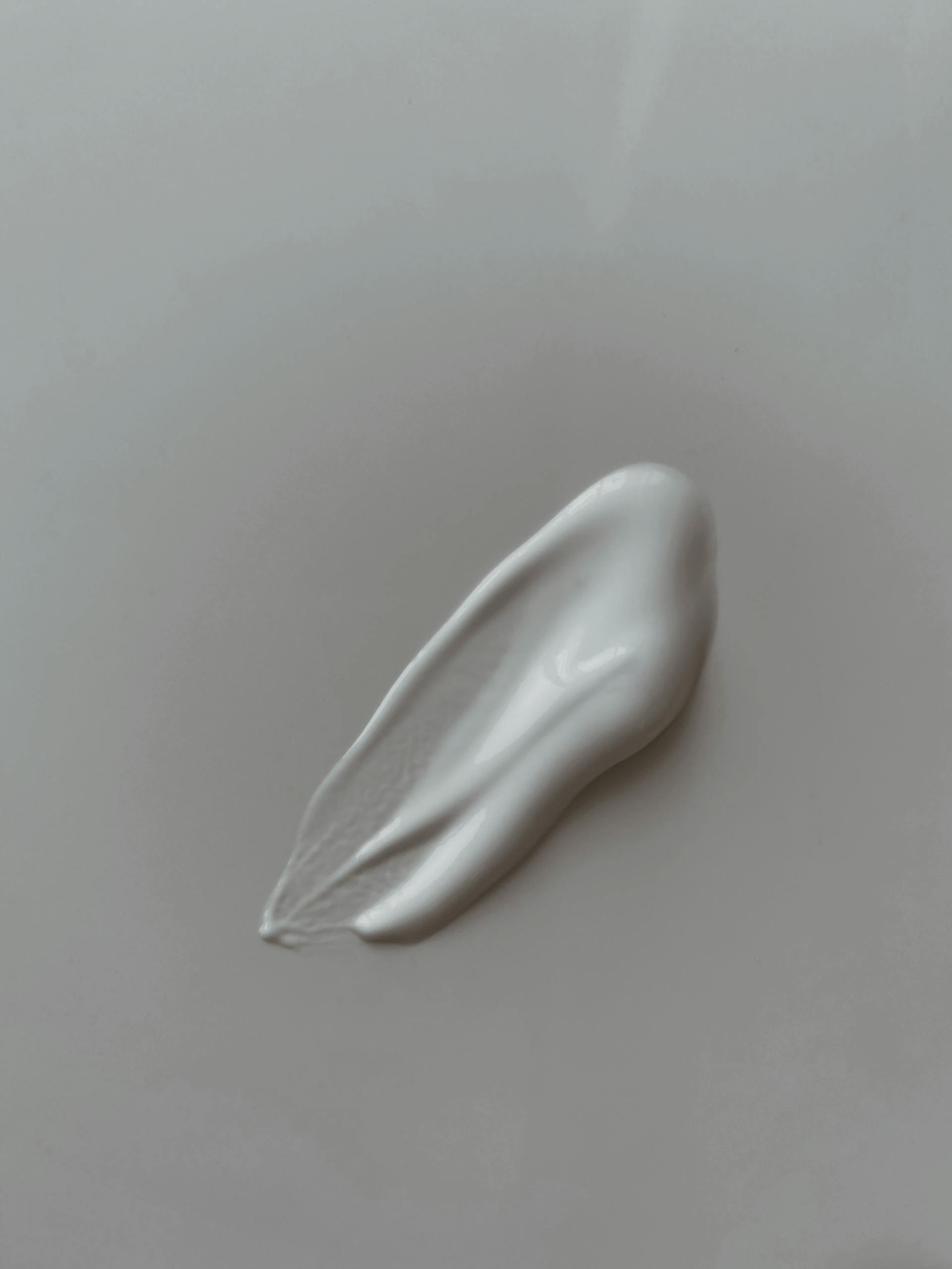 Smooth and creamy white lotion texture on neutral background