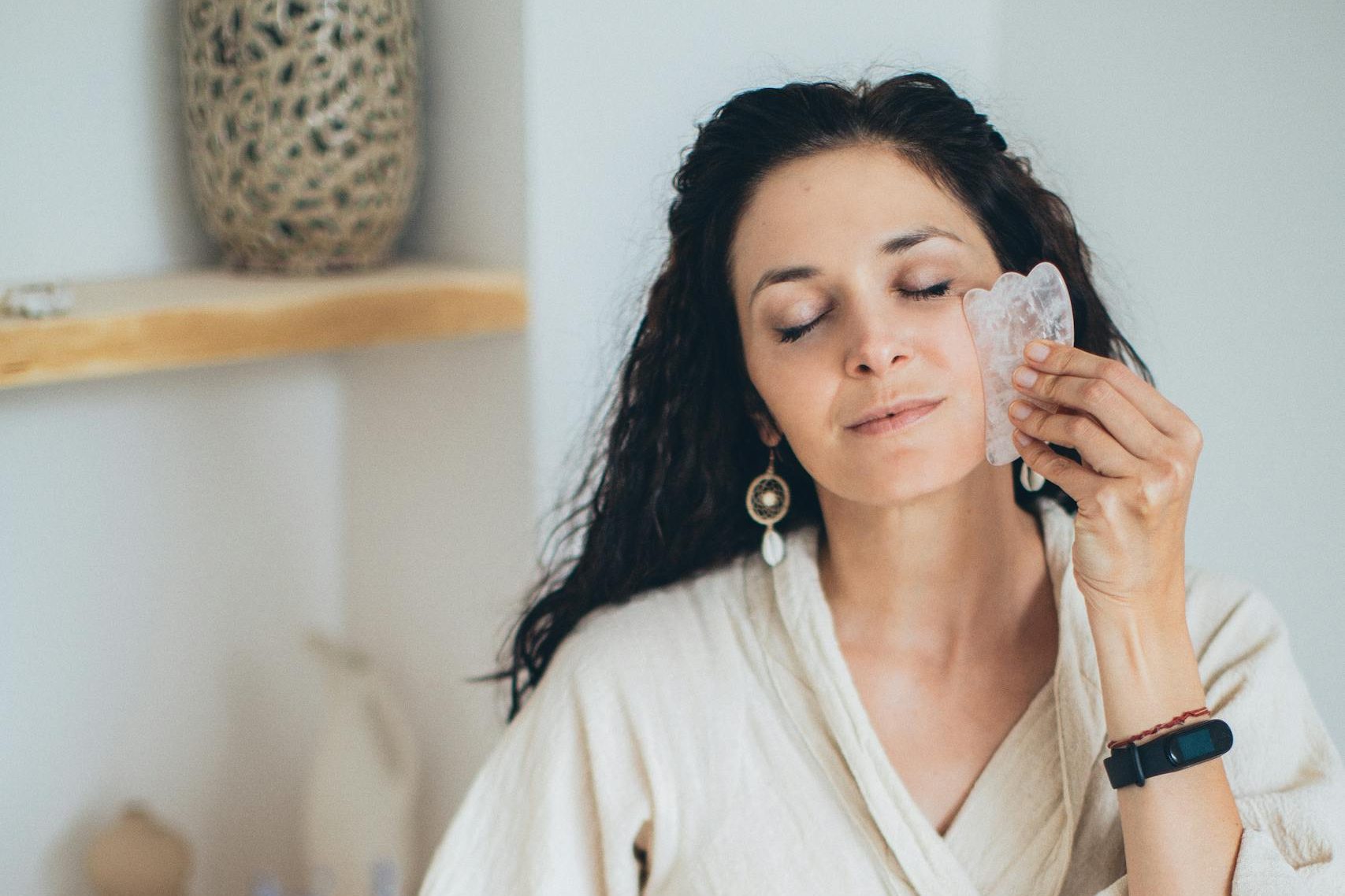 Woman using jade gua sha tool for perimenopausal skin