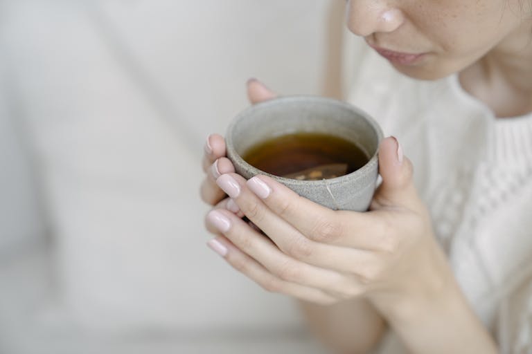 Close-up of a woman holding a hot cup of tea, illustrating warmth and relaxation.